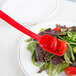 A red Cambro salad bar spoon in a salad.