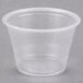 A clear plastic Dart souffle cup on a grey surface.