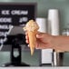 A hand holding a Dutch Treat ice cream cone over a counter.