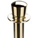 A brass Aarco rope style crowd control stanchion with a round metal cap.