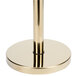 A gold metal Aarco rope style crowd control stanchion with a round base.