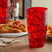 A red GET Bahama plastic tumbler with ice on a table with pizza.