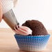 A person using an Ateco closed star piping tip to frost a cupcake.