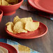 A close up of a red Tuxton Concentrix China plate with potato chips on it.