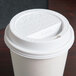 A Solo white plastic travel lid on a white paper cup.