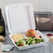 A Dart white foam takeout container with three compartments holding salad and macaroni and cheese.
