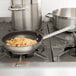 A Vollrath Centurion stainless steel non-stick fry pan with spaghetti and sauce on a stove.