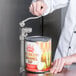 A person using a Choice Prep Light Duty Manual Can Opener to open a can of caramel.