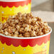 A bucket of popcorn with red and yellow containers filled with caramel popcorn.