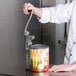 A chef using a Choice Prep Standard Duty #10 Manual Can Opener to open a can of food in a professional kitchen.