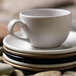 A close-up of a white Libbey Driftstone porcelain mug on a stack of plates.