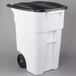 A white Rubbermaid rectangular trash can with black wheels and lid.