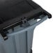 A close-up of a Rubbermaid grey wheeled rectangular trash can with a lid.