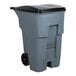 A grey Rubbermaid commercial trash can with black wheels and lid.