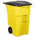 A yellow Rubbermaid commercial trash can with black wheels and lid.