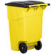 A yellow Rubbermaid commercial trash can with black wheels and lid.