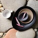 A Libbey onyx satin matte organic porcelain coupe plate with a bowl of dragon fruit on a stone surface.