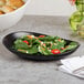 A Libbey Driftstone onyx porcelain coupe plate with a salad on it.