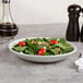 A bowl of salad with tomatoes and cheese in a white Libbey Driftstone porcelain bowl.