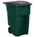 A green Rubbermaid wheeled rectangular trash can with a black lid.