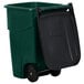 A green Rubbermaid wheeled rectangular trash can with a black lid.