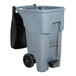 A grey Rubbermaid commercial trash can with black wheels and handles.