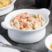 A white Libbey porcelain casserole dish filled with pasta and vegetables on a table.