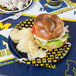 A Creative Converting University of Michigan paper plate with a sandwich and chips on it.