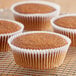 A close-up of a carrot muffin in a white fluted baking cup.