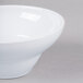 A close-up of an Elite Global Solutions white melamine bowl on a gray surface.