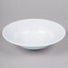 A white Elite Global Solutions melamine bowl with a swirl design on a gray surface.
