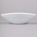 A white oblong Elite Global Solutions melamine bowl with a white swirl design on a gray surface.