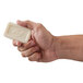 A hand holding a white square Dial deodorant soap bar.