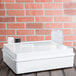 A white Elite Global Solutions melamine box lid on a table with a glass and bottle inside.