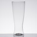 A close-up of a clear WNA Comet plastic pilsner glass with a smooth bottom containing a small amount of liquid.
