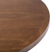 A BFM Seating round wooden table top with a wooden base.