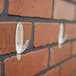 A clear plastic Command hook attached to a brick wall.
