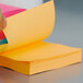 A hand holding a yellow 3M Post-It note pad with white paper.