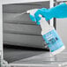 A hand in blue glove spraying Noble Chemical Oven Guard from a spray bottle.