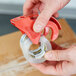 A hand using a red 3M Scotch tape dispenser to seal a box.