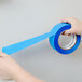 A hand holding a roll of 3M ScotchBlue blue painter's tape