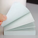 A hand holding a fan-folded stack of pastel colored Post-It notes.