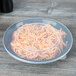 A clear Fineline plastic catering bowl lid on a table over a bowl of spaghetti.