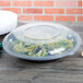 A black Fineline low profile plastic catering bowl filled with salad on a table.