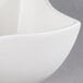 A white American Metalcraft Squavy porcelain sauce cup with a curved edge.