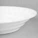 A close-up of a Fineline white low profile plastic catering bowl with a circular rim.