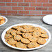 A white Fineline plastic catering tray holding chocolate chip cookies on a table.