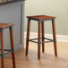 Two Lancaster Table & Seating Rustic Industrial Backless Bar Stools with Antique Walnut Finish on a counter.