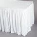 A white shirred pleat table skirt on a table with a white tablecloth.