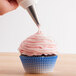 A person using an Ateco closed star piping tip to frost a cupcake.